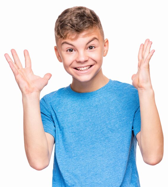 Foto retrato emocional a media longitud de un adolescente caucásico con una camiseta azul adolescente sorprendido mirando a la cámara niño guapo y feliz aislado sobre un fondo blanco