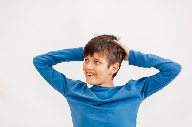 Retrato emocional de medio cuerpo de un muchacho adolescente caucásico con camiseta azul. Adolescente sorprendido mirando a cámara. Niño feliz guapo, aislado sobre fondo blanco.