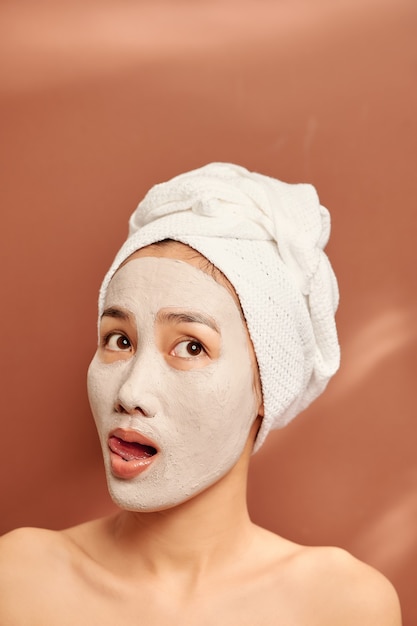 Retrato emocional de una mujer joven desnuda hermosa feliz y positiva con una máscara cosmética de arcilla en su rostro