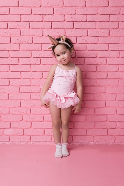 retrato emocional de una niña asiática con un traje de bailarina con fondo rosa