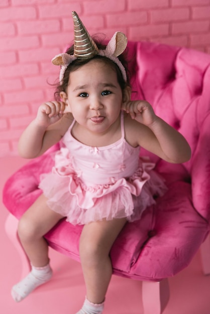 Foto retrato emocional de una niña asiática con un traje de bailarina con fondo rosa