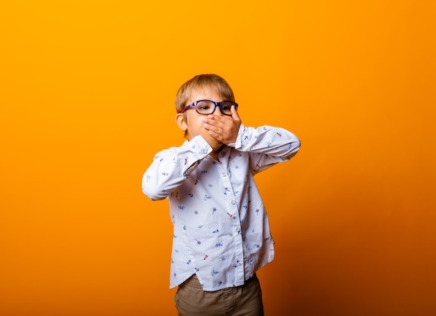 Retrato emocional de un niño con gafas. Un niño sorprendido mira a la cámara.