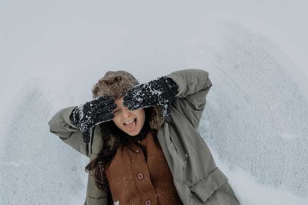 retrato emocional positivo de uma bela mulher sorridente deitada na neve e posando para uma foto