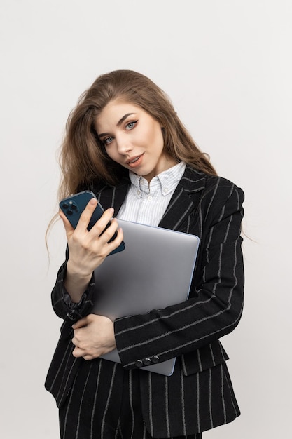 Retrato de un empleado de oficina con una computadora portátil y un teléfono inteligente sobre un fondo blanco Jefe profesional del departamento