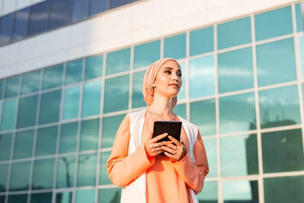 Retrato de una empresaria árabe en hijab sosteniendo una tableta.