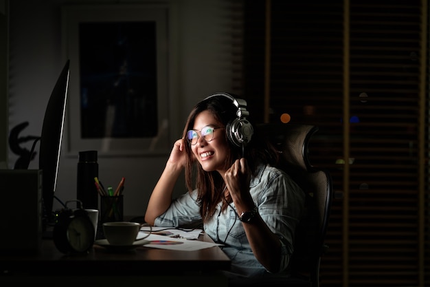 Retrato de una empresaria asiática que escucha la música a través de auriculares y teléfonos móviles inteligentes