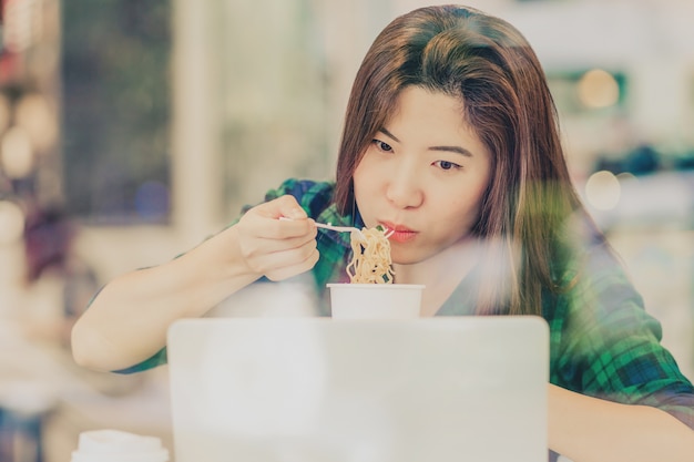 Retrato de empresaria asiática en traje casual comiendo fideos