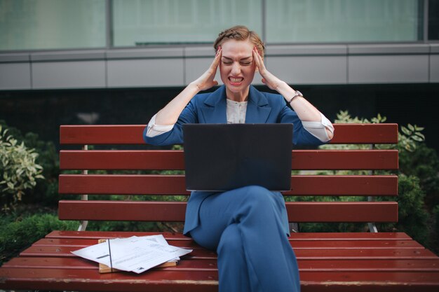 Retrato de empresaria estresante gritando. Ella sostiene su cabeza con sus manos