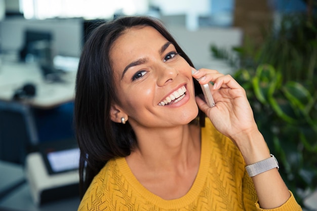 Retrato de una empresaria linda feliz hablando por teléfono en la oficina