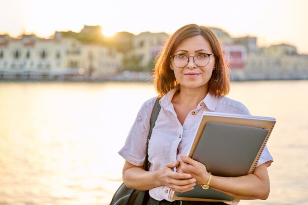 Retrato empresaria de mediana edad con portátil en la mano mirando a la cámara