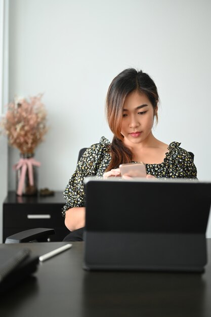 Retrato de una empresaria sentada en el espacio de trabajo y trabajando en tableta