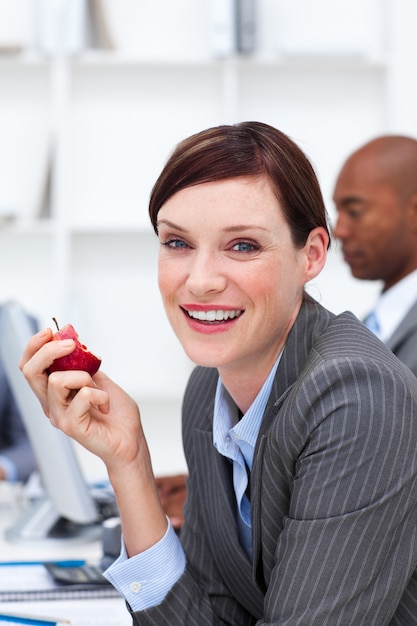 Retrato de una empresaria sonriente comiendo una manzana