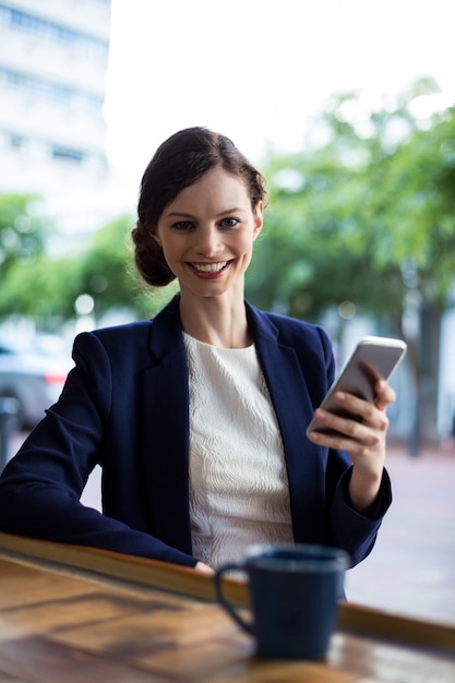 Retrato de empresaria mediante teléfono móvil en el mostrador