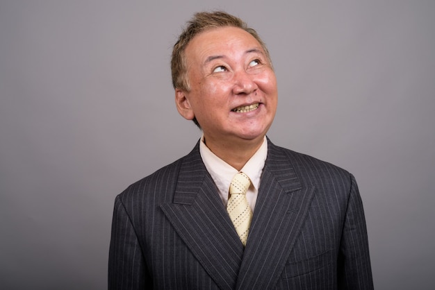 Retrato del empresario asiático maduro contra un fondo gris
