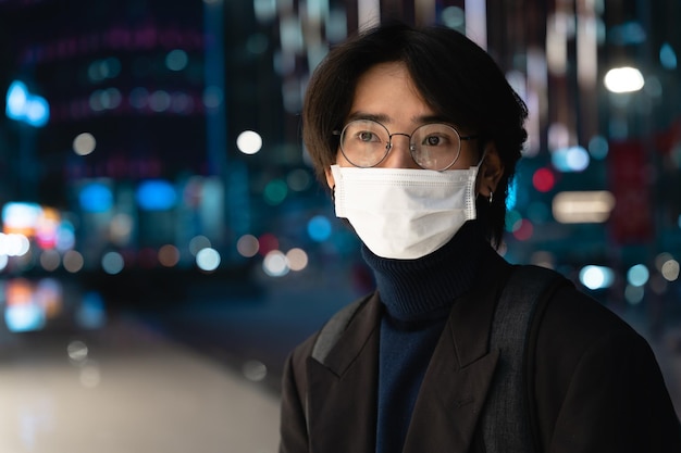 Retrato de un empresario asiático con una máscara, en la calle por la noche