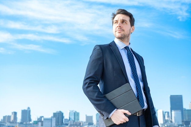 Retrato de un empresario, cielo azul y edificios de la gran ciudad