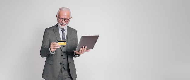 Retrato de un empresario con una computadora portátil y una tarjeta de crédito haciendo compras en línea sobre un fondo blanco