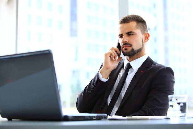 Retrato del empresario hablando por teléfono móvil en la oficina