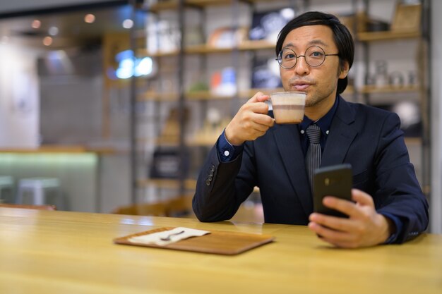 Retrato del empresario japonés sentado dentro de la cafetería.