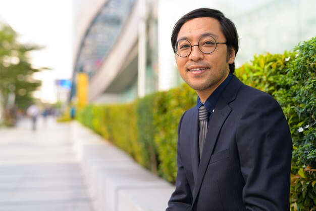 Retrato del empresario japonés tomando aire fresco con la naturaleza en la ciudad al aire libre