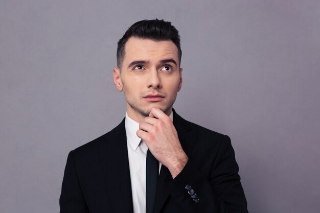 Foto retrato de un empresario pensativo mirando hacia arriba sobre la pared gris