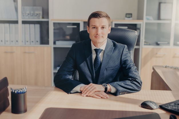 Retrato del empresario próspero atractivo viste traje negro, camisa blanca con corbata