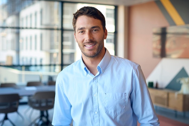 Retrato de un empresario sonriente de pie en una oficina vacía