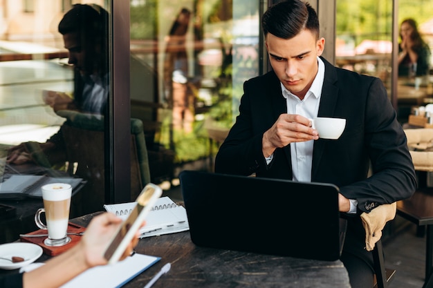 Retrato del empresario sosteniendo una taza de café y mirando la pantalla del portátil