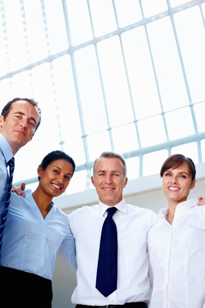 Foto retrato de empresarios y sonrisa con ángulo bajo en el cargo con abrazo y unidad para la diversidad en la comunidad equipo de hombres y mujeres juntos para la colaboración corporativa o asociación global