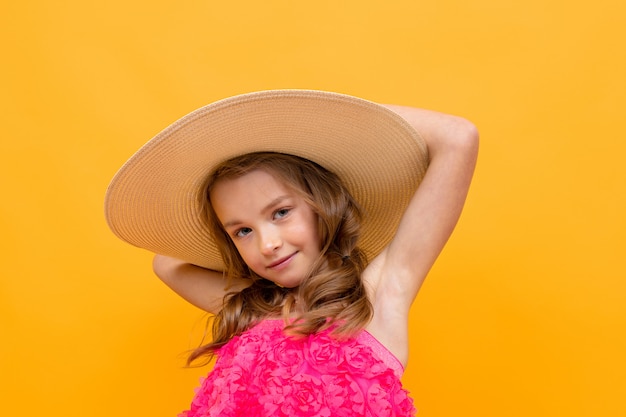 Retrato de un encantador niño lindo con un sombrero de paja sobre un fondo amarillo