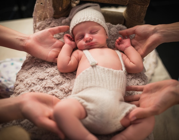 Foto retrato de un encantador niño recién nacido en un gorro de punto y pantalones cortos durmiendo en una cama acogedora