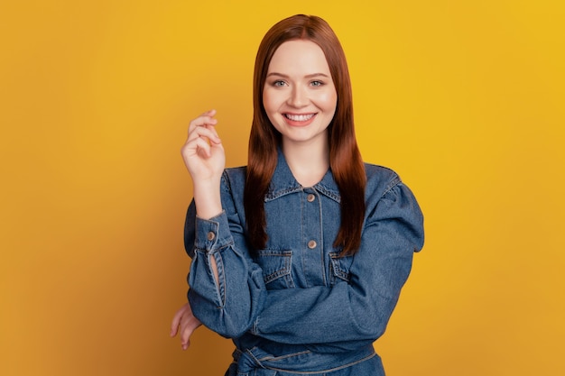 Retrato de encantadora dama hermosa adorable mantenga la mano brillante sonrisa radiante sobre fondo amarillo