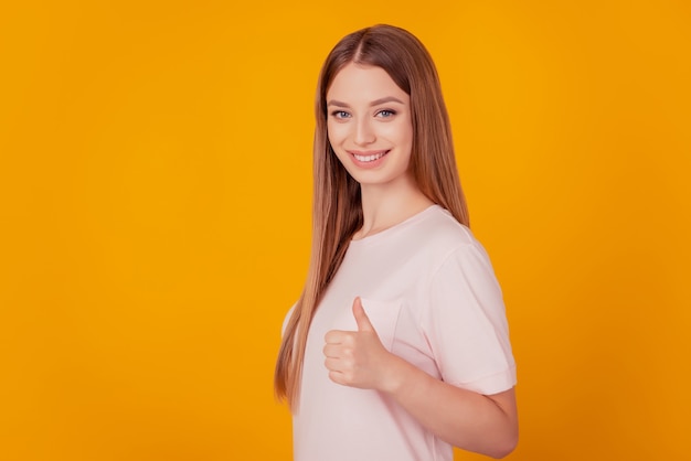 Retrato de encantadora dama rubia consejera mostrar pulgar hacia arriba sonrisa blanca sobre fondo amarillo