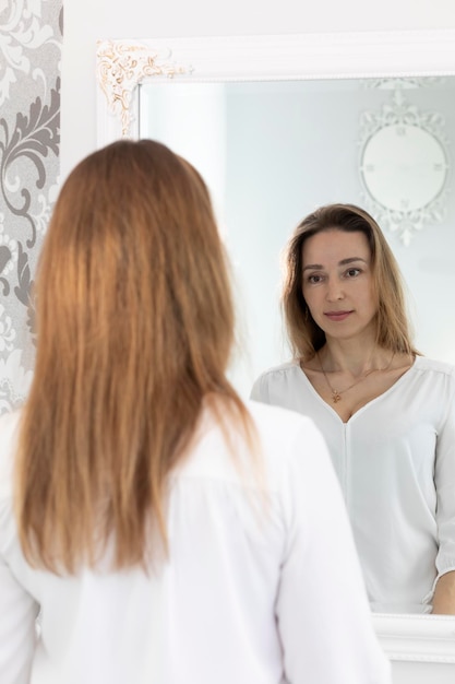 Retrato de encantadora hermosa morena caucásica mujer de 40 años mirándose en el espejo y sonriendo sana