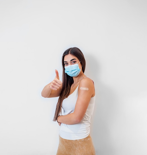 Retrato de una encantadora joven adulta con una máscara protectora que da su aprobación en el hospital