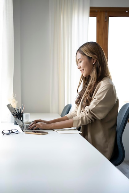Retrato de una encantadora mujer de negocios sentada en una oficina moderna y trabajando con una laptop