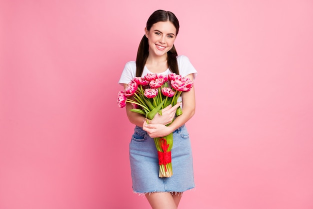 Retrato de encantadora niña alegre sosteniendo en las manos ramo de flores frescas