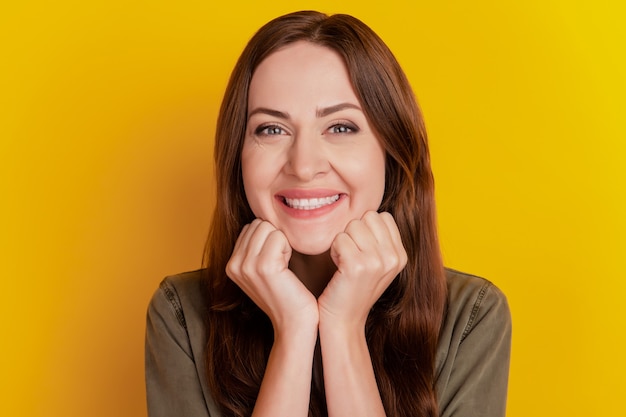 Retrato de encantadora niña bonita dulce brazos mejillas sonrisa brillante sobre fondo amarillo