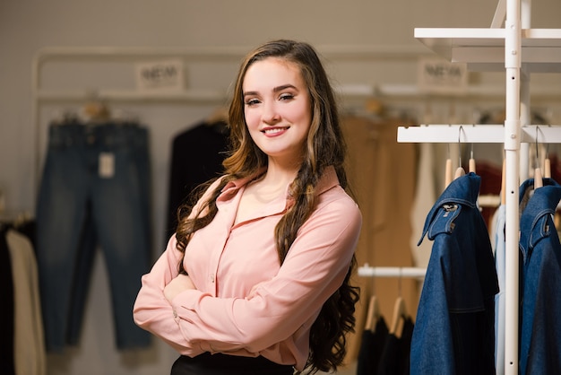 Retrato de encantadora vendedora alegre en tienda de ropa