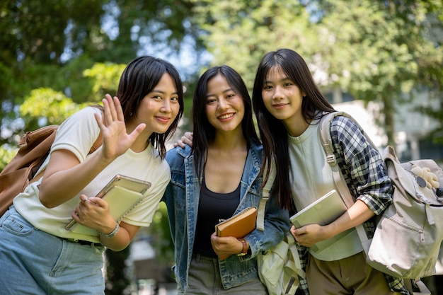 Retrato de encantadoras y amigables estudiantes universitarias asiáticas saludando y sonriendo a la cámara