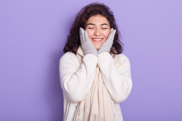 Retrato de enérgico atractivo femenino cerrando los ojos, sonriendo