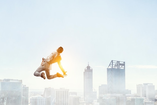 Retrato de un enérgico hombre de negocios saltando al aire libre. Técnica mixta