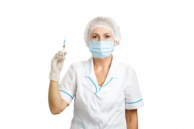 Retrato de enfermera con jeringa, vista frontal. Vacunación protectora: Doctora con jeringa y mascarilla en blanco de cerca.