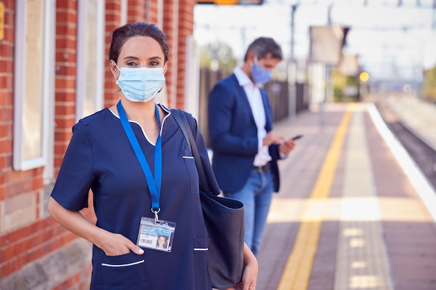 Retrato de una enfermera en una plataforma ferroviaria que usa una máscara facial de PPE que se desplaza al trabajo durante la pandemia