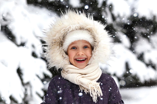 Retrato engraçado de criança na neve do inverno. Menina sorrindo no parque nevado. Férias com a família no inverno