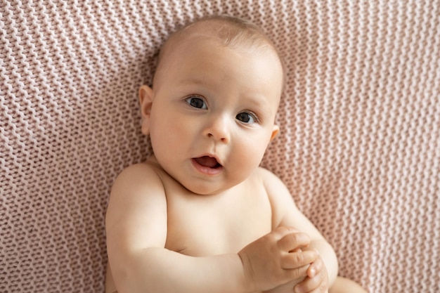 Retrato engraçado de um bebê em uma manta de malha rosa Estilo de vida Luz de fundo Espaço para texto