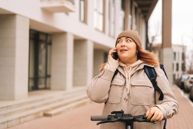 Retrato de la entrega de alimentos de mensajería femenina con una gran mochila térmica en la espalda hablando por teléfono inteligente con