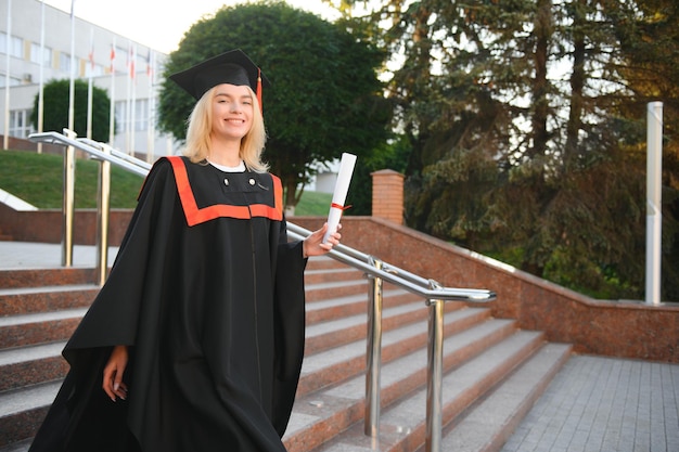 Foto retrato de una entusiasta estudiante universitaria graduada con gorra y bata celebrando su diploma