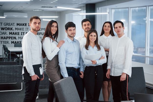 Retrato de equipo joven en ropa clásica en la moderna oficina bien iluminada