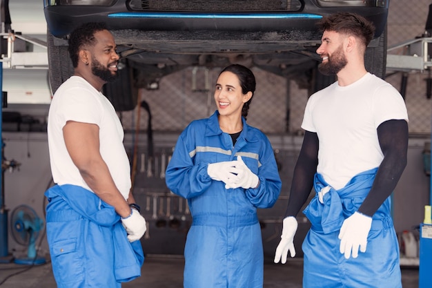 Foto retrato de un equipo de mecánicos sonrientes en un taller de reparación de automóviles hablando mientras están de pie